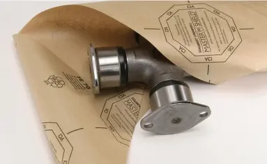 Eine Metallteil wird in VCI-Papier eingewickelt