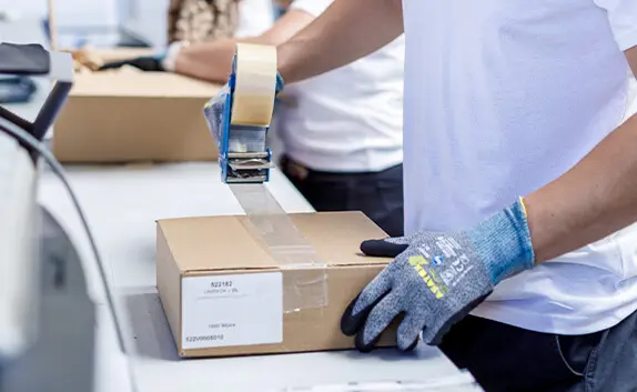 Logistikmitarbeiter verklebt einen 2-welligen Karton mit Packband