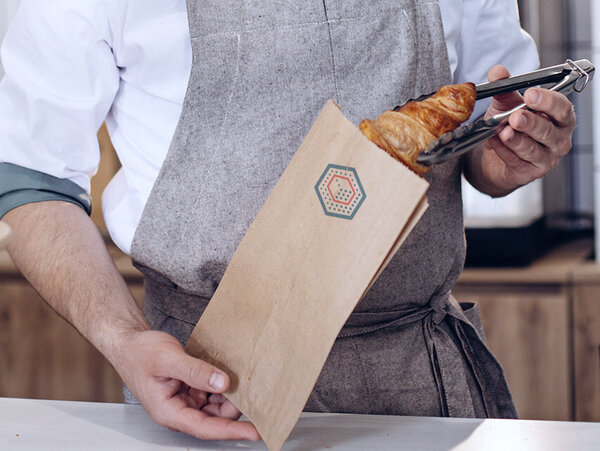 Bäcker verpackt Backwaren in einem Faltenbeutel