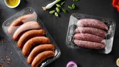 Bild mit verpackten Würsten vergrößern Auf einem Tisch liegen 2 mit Non-PVC-Lebensmittelfolie verpackte Knacker und Bratwürste.