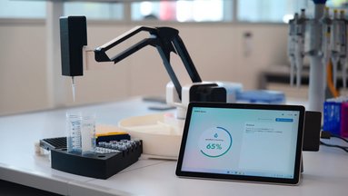 Der Roboterarm mit Pipette von der goodBot UG befüllt ein Reagenzglas mit Flüssigkeit.