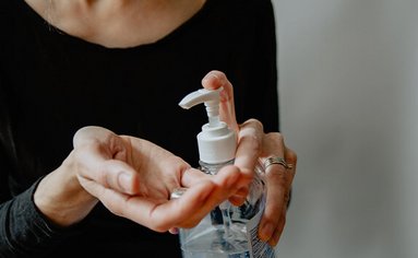 Eine Frau verteilt Desinfektionsmittel mit einem Spender in die Hände.