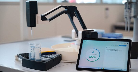 Auf einem Tisch steht ein Roboter-Arm, der per Tablet gesteuert wird.