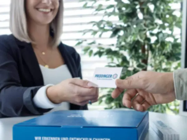 Mitarbeiterin von PRODINGER übergibt eine Karte mit Kontakt-Informationen
