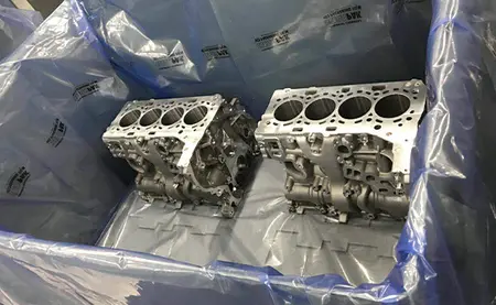 2 Motorblöcke liegen in einer Kiste, die mit VCI-Folie ausgelegt ist.