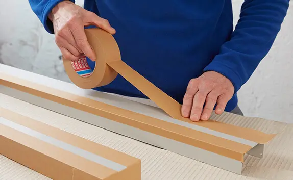 Ein Mann klebt Leisten mit Kreppband ab.