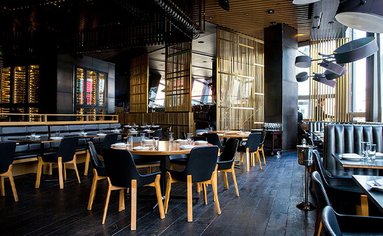 Eine modern eingerichtet Kantine mit schwarzen Holzboden, schwarz-braunen Stühlen und Tischen.