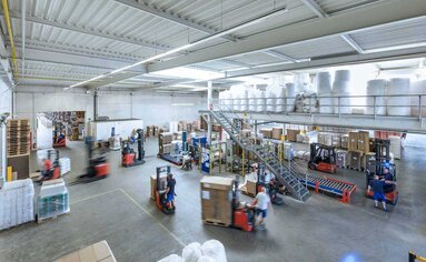 Logistikzentrum im Hochbetrieb mit Paletten-Versandstraße mit Stretchmaschine und Umreifungsmaschinen.