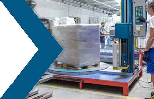 Ein Logistikmitarbeiter bedient eine Stretchmaschine, die eine Palette mit Paketen einwickelt.