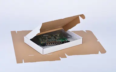 Gefalteter Karton aus einer Stanzverpackung, in der ein Platine liegt.
