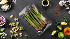 Bild mit verpackten Spargel vergrößern Auf einem Tisch liegt eine Kunststoffverpackung mitmit Non-PVC-Lebensmittelfolie, in dem Spargel verpackt wurde.