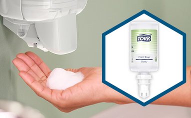 Ein Seifenschaumspender schäumt eine Hand mit Tork Reine Hand Schaumseife ein.