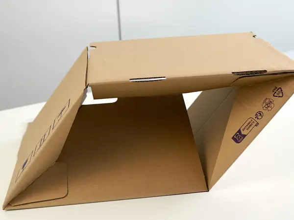 Ein Karton mit Automatikboden liegt auf einem Tisch und wird aufgerichtet.