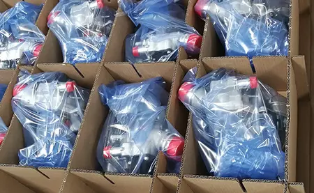 In einem Karton mit Gefache liegen Produkte aus Metall, die in VCI-Folie eingepackt sind.