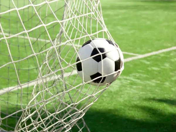 Ein Fußball fliegt in ein Tor-Netz.