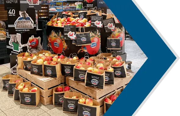 Ansicht der KANZI®-Aktion im Einkaufsmarkt mit vielen Papiertaschen.