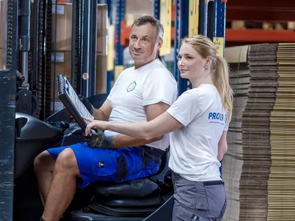 Logistik-Mitarbeiter stehen in einem modernen Hochregallager voller Verpackungsartikel