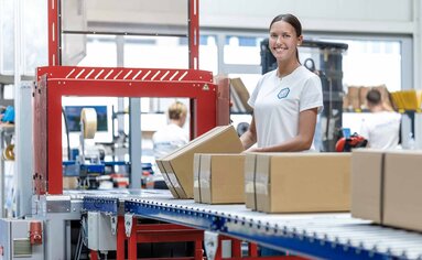 Kartonagen werden auf vollautomatischer Paket-Packstraße mit Klebeband verschlossen